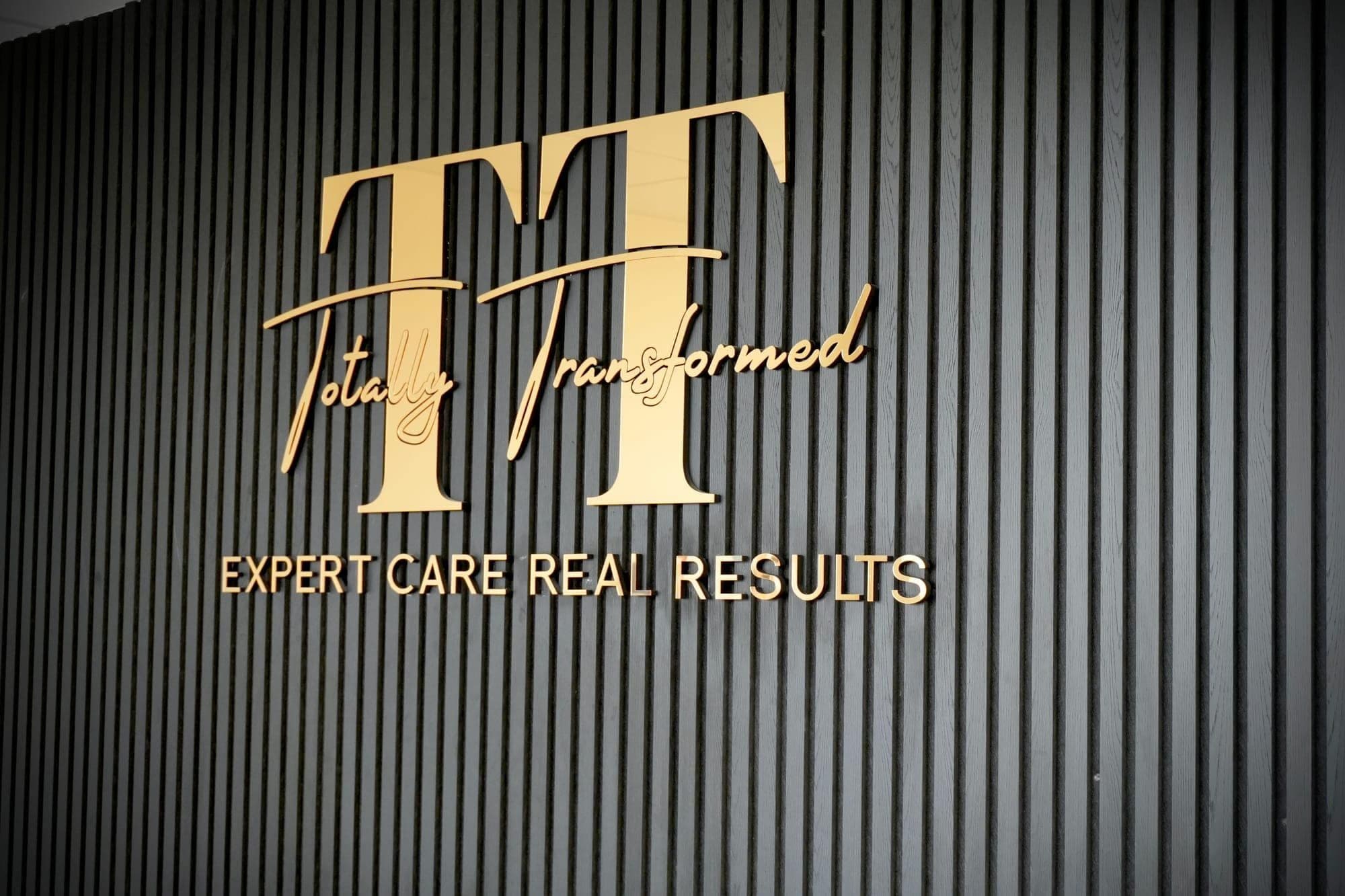 The gold Totally Transformed logo, Expert Care, Real Results, at the Forest Hall clinic